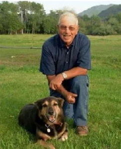 A person kneeling on grass beside a dog